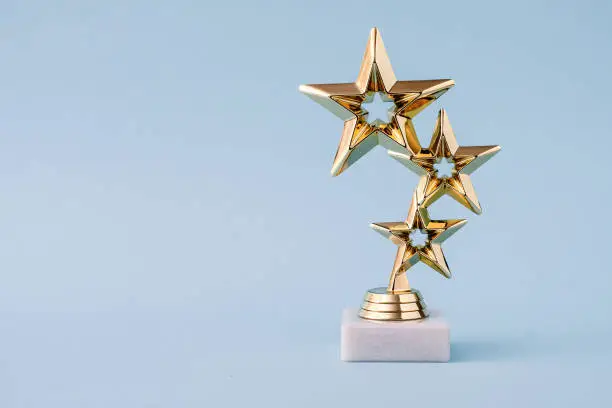 Photo of Three star awards for leader and ranking. Golden shiny prize on a pastel blue background.