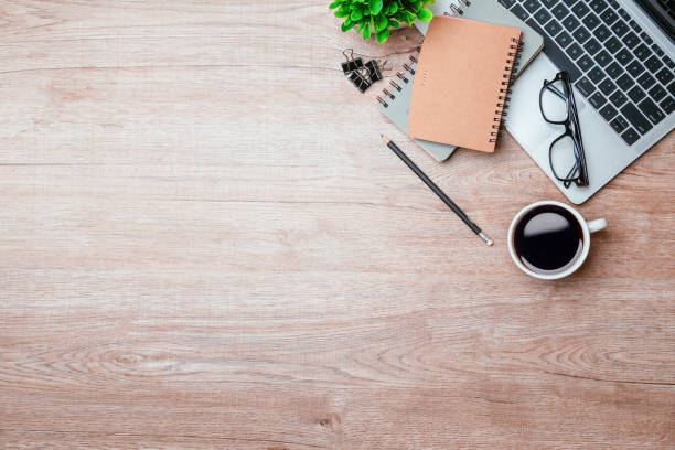 istock Work from home. desk office with laptop, blank notepad, coffee cup and pen on wood table. Flat lay top view copy spce. 1340404390