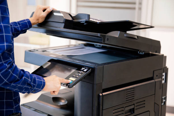 gli uomini d'affari premono il pulsante sul pannello per utilizzare la fotocopiatrice o la stampante per la stampa e la scansione della carta da documento in ufficio. - stampante foto e immagini stock