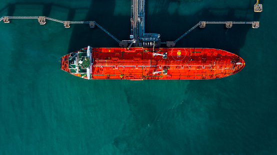 Aerial view tanker ship vessel unloading at port, Business import export oil and gas petrochemical with tanker ship transportation oil from dock refinery, Loading arm oil and gas offshore platforms.