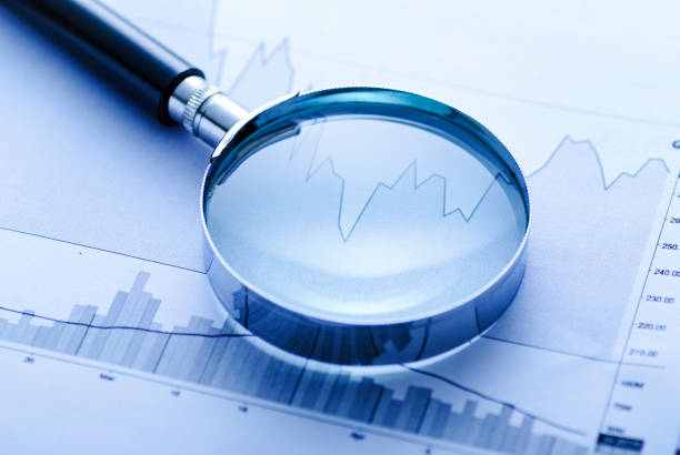 istock Magnifying glass with business graphs 1340408356
