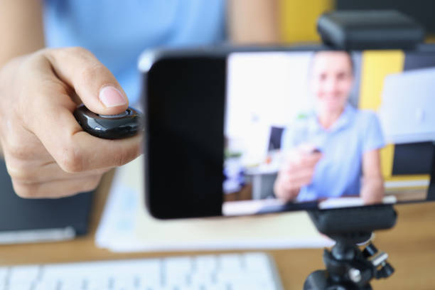 istock Woman presses button on control panel and shoots video on smartphone on tripod 1340411860