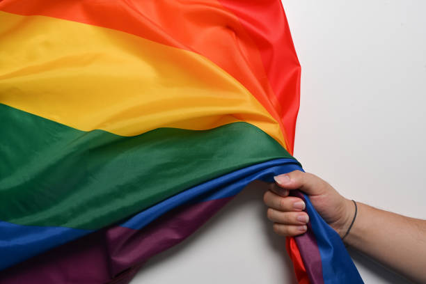 istock Man hand holding LGBT pride flag on white background. LGBT concept. 1340414640