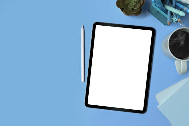 istock Top view digital tablet, stylus pen and supplies on blue background. 1340415601