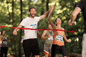 Happy athletic couple crossing the finish line during marathon in nature.