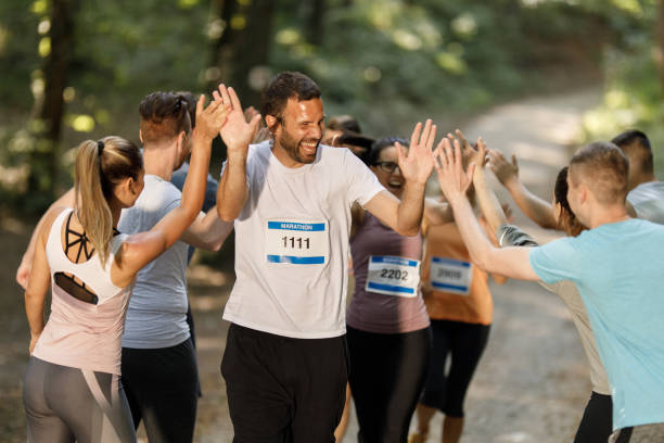 istock Happy marathon runner greeting group of athletes at finish line. 1340416476