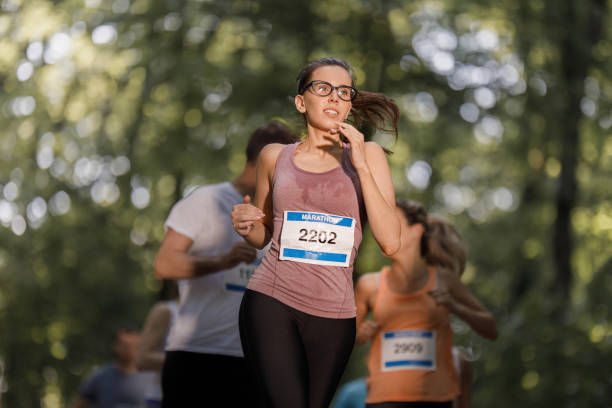 part of young woman with start number during marathon run