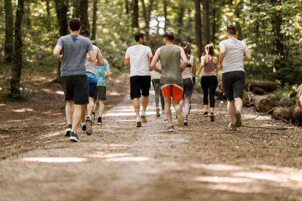 istock Back view of large group of athletes running a marathon in forest. 1340417331