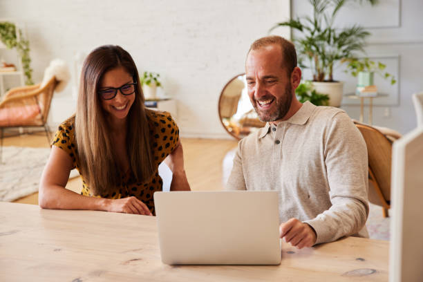 istock Two businesspeople laughing at something online while working in an office 1340419306