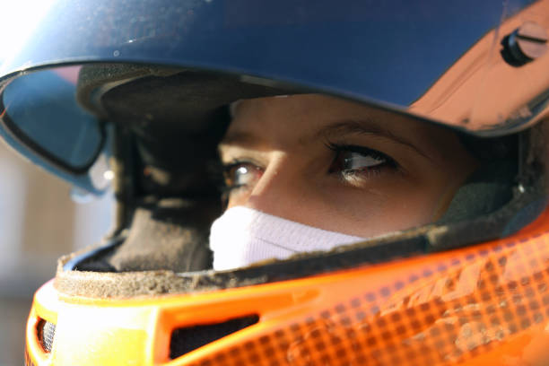 Symbol image: Female race car driver wears helmet and balaclava (Model released) Symbol image: Female race car driver wears helmet and balaclava (Model released) race car driver stock pictures, royalty-free photos & images