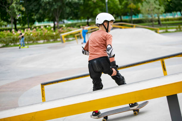 kleiner junge skateboarding im park - skateboard court stock-fotos und bilder