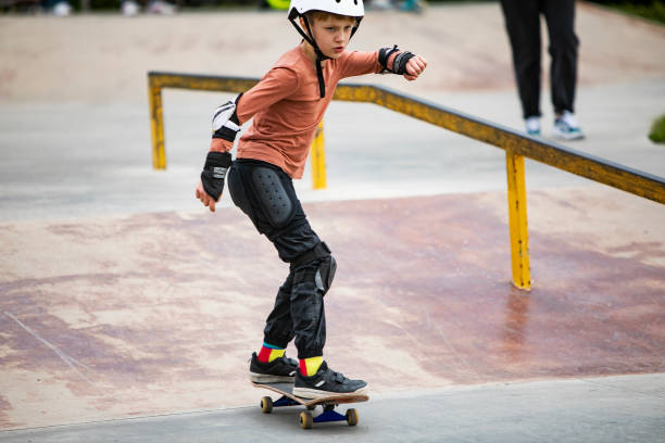 kleiner junge skateboarding im park - skateboard court stock-fotos und bilder