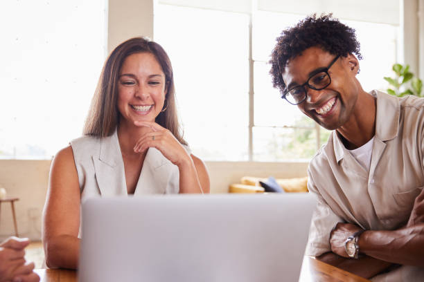 istock Two diverse young businesspeople laughing while working on a laptop 1340423859