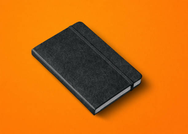 black closed notebook isolated on orange black closed notebook mockup isolated on orange moleskin stock pictures, royalty-free photos & images