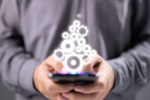 istock Businessman holding gears and smartphone in palms 1340425761