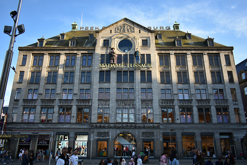 Building facade of Madame Tussauds wax museum and Peek and Cloppenburg department store on a sunny afternoon with people visiting the area.