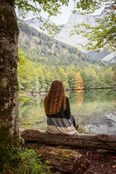 istock Young woman sitting on a log by a lake 1340431397