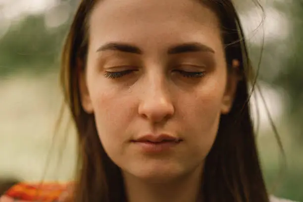 Photo of Depressed young woman in a outdoors. The girl is crying. Woman without make-up.