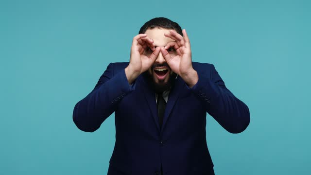 Man looks through fingers on eyes, making binoculars gesture