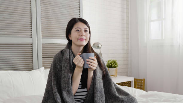 istock asian woman drinking hot tea sitting on bed 1340435243