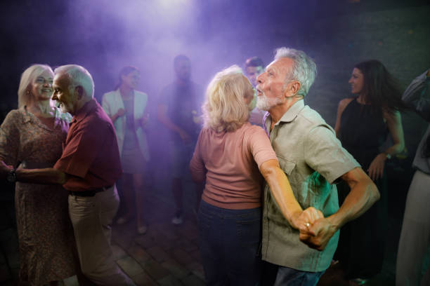 Happy mature couples dancing in a disco. Happy senior couples having fun while dancing during nightlife in a disco. middle aged couple dancing stock pictures, royalty-free photos & images