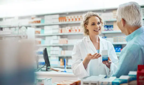 Photo of Cropped shot of an attractive young chemist helping a senior male customer in her pharmacy