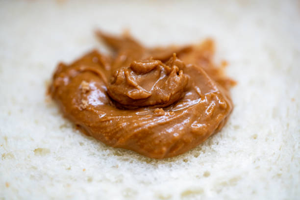 Close up woman spreading peanut butter cream over bread slice