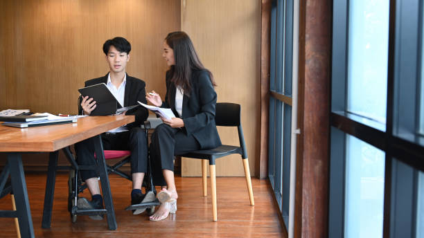 istock Disabled man working with his colleague in modern office. 1340436747