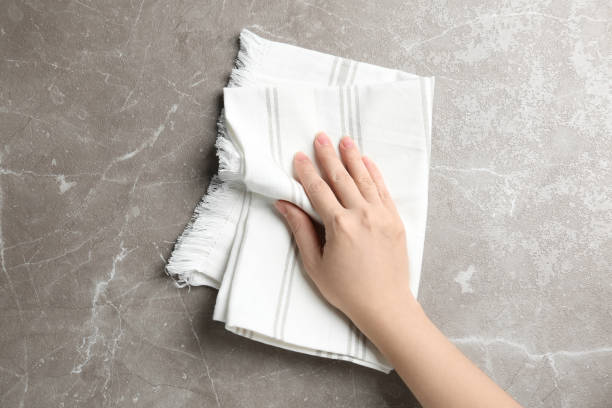 istock Woman wiping grey marble table with kitchen towel, top view 1340441052