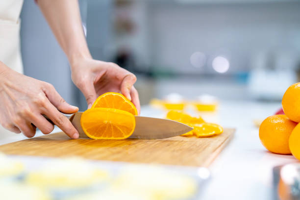 istock Asian woman cutting fresh fruit for making fruit tart in the kitchen. 1340441170