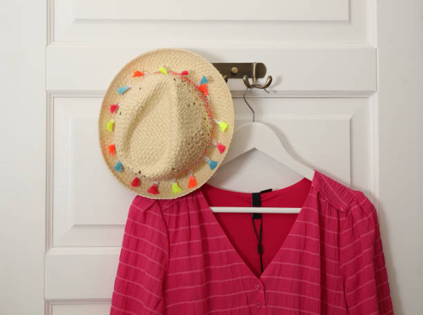 istock Clothes hooks with blouse and straw hat on white door 1340443206