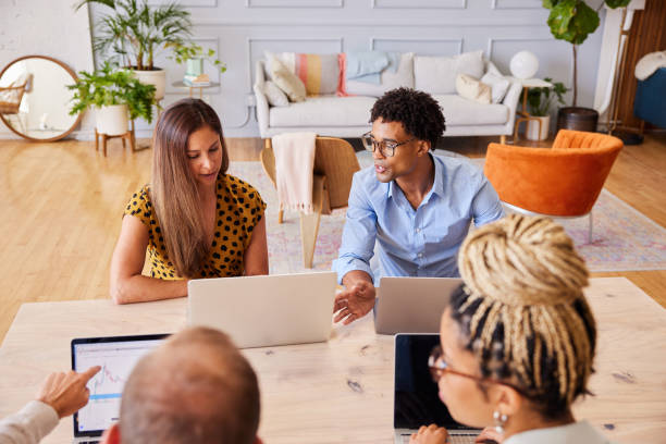 istock Diverse young businesspeople talking while working on laptops in a office 1340446291