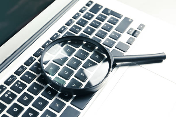 istock Magnifying glass and modern laptop on table, closeup. Search concept 1340446629