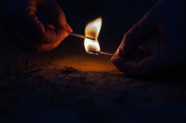 two hands with burning matches in the dark. man passes flame fro - fire match women flame imagens e fotografias de stock
