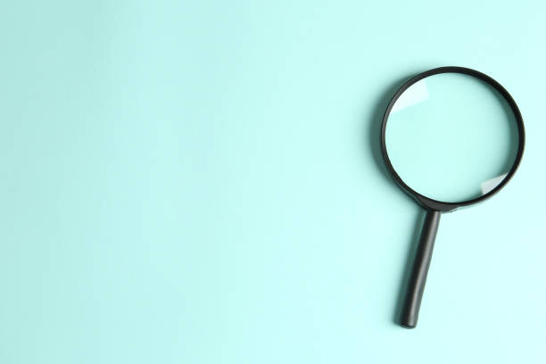 istock Top view of magnifying glass on light blue background, space for text. Search concept 1340446909
