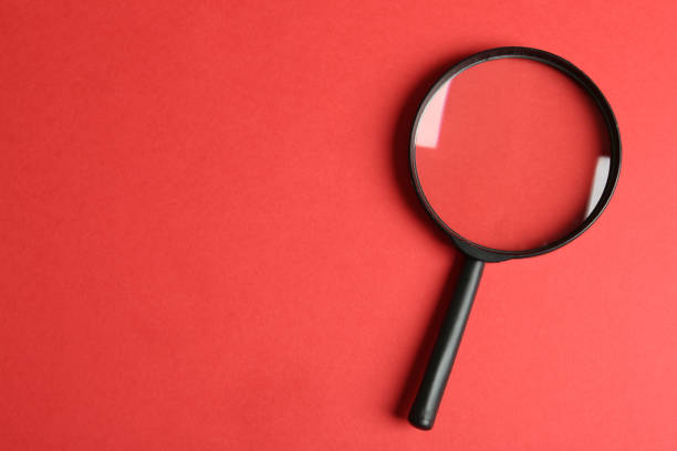istock Top view of magnifying glass on red background, space for text. Search concept 1340446911