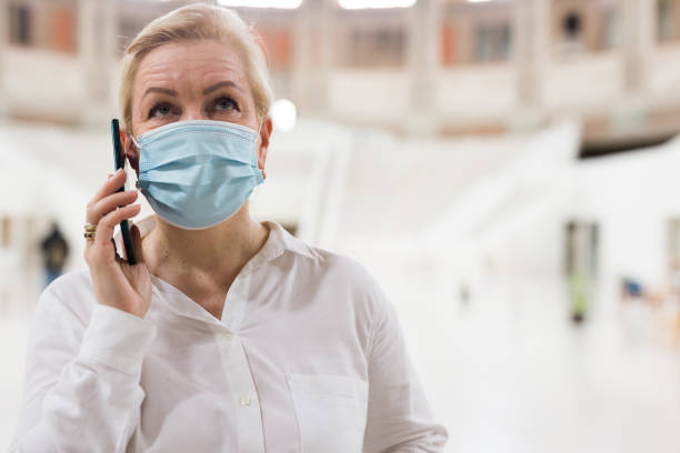 istock Lady in protective face mask speaking on smartphone 1340450476