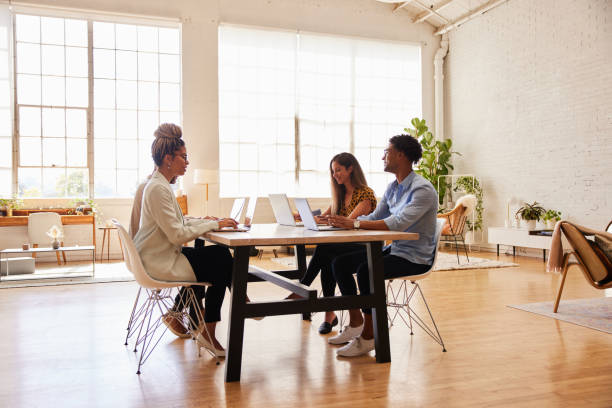 istock Group of diverse young businesspeople working on laptops around an office table 1340451203
