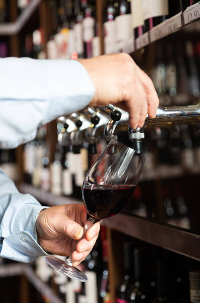 istock Hands of bartender pouring red wine from tap 1340452135