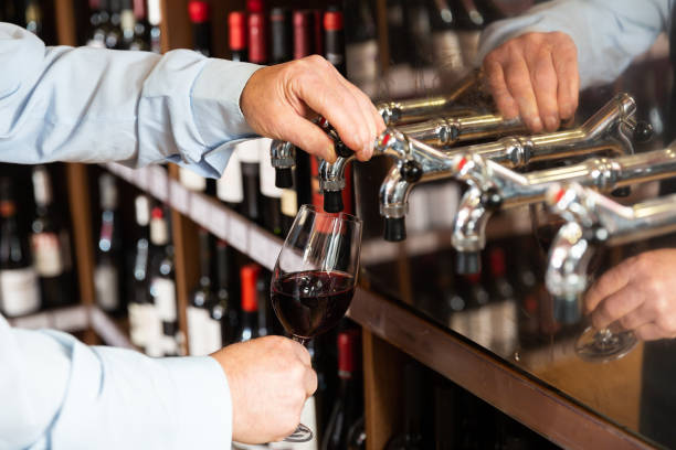 istock Hands of bartender pouring red wine from tap 1340452136