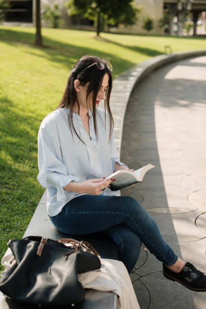 istock Young woman reading a book outdoors 1340452902