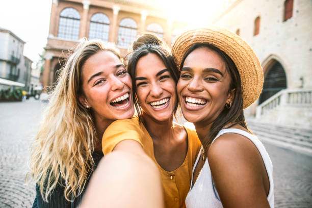 three young women taking selfie portrait on city street - multicultural female friends having fun on vacation hanging outdoor - friendship and happy lifestyle concept - family tourist europe vacations imagens e fotografias de stock