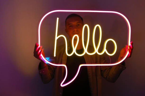 istock Handsome young man holding pink and yellow neon sign hello. 1340455988
