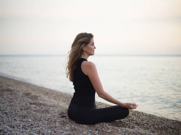 istock young beautiful woman meditates while sitting by the sea 1340456302