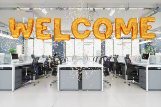 Photo of Welcome Party To New Worker In Open Plan Office With Gold Colored Welcome Foil Balloons And Confettis.