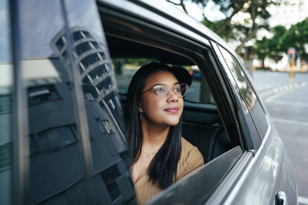 Smiling young woman looking at the city from the backseat of a taxi stock photo