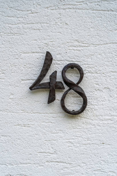 istock Metal house number 48 on a white stucco wall background 1340461196
