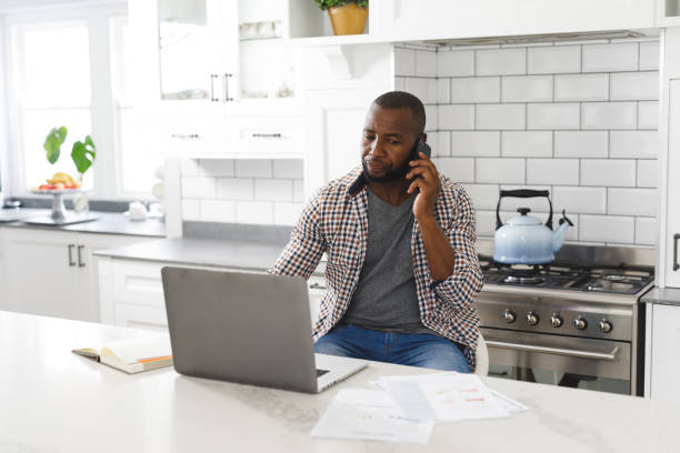 istock African american man sitting in kitchen working using laptop and smartphone 1340462185