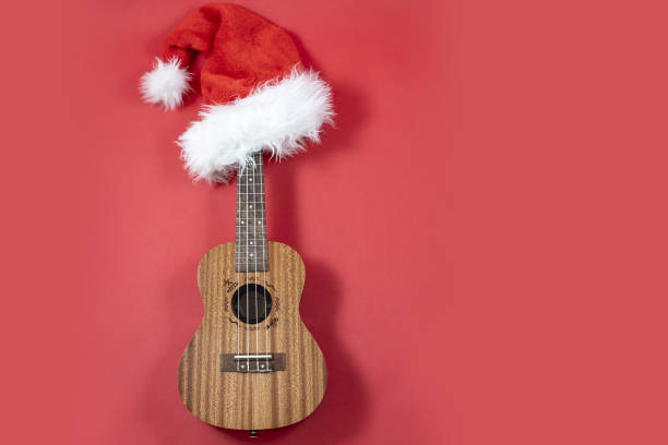 istock Ukulele with copy space Christmas guitar on a red background. Christmas hat. An 1340462615