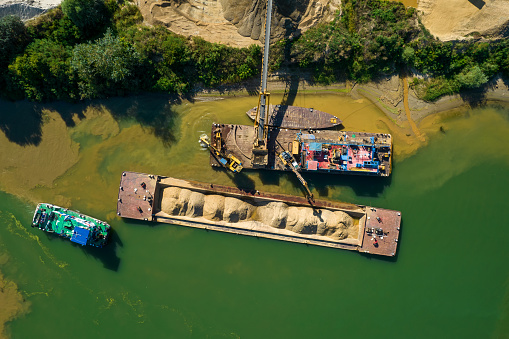 Aerial view of quarry. Earth mover loading sand on barge.